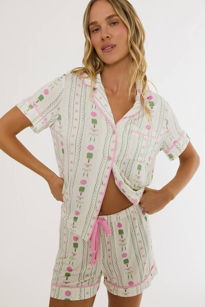 Woman wearing a patterned pajama set with pink accents on a white background