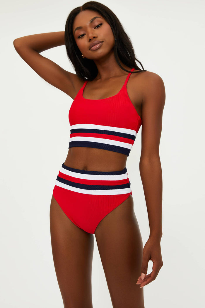 This image features the "Millie Bottom American Colorblock," a stylish high-waist swim bottom. The model is wearing a vibrant swimsuit in red, white, and blue stripes, which offers a bold and patriotic look.