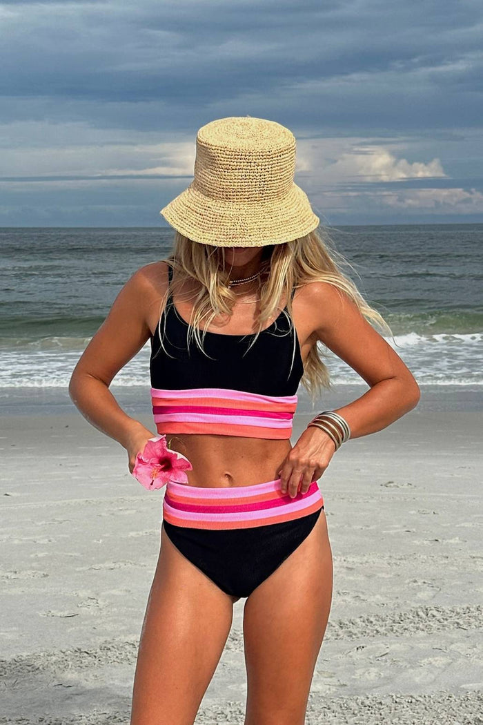 Woman in a colorful striped swimsuit and sun hat on a beach