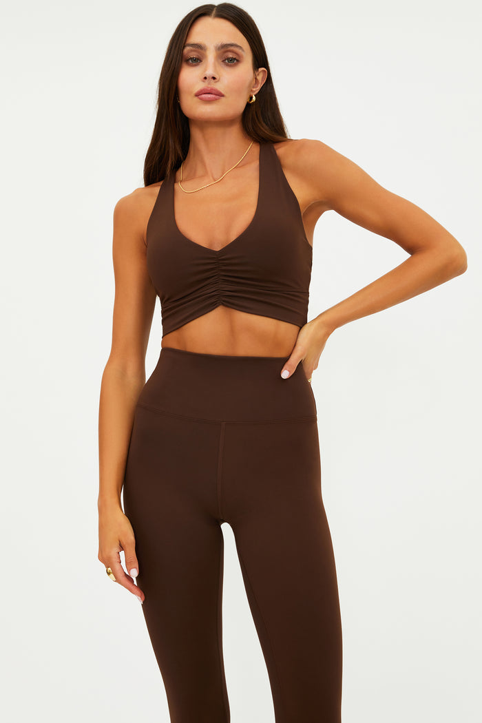 Woman wearing a brown sports bra and leggings on a white background