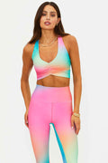 Woman wearing a colorful rainbow sports bra and leggings set on a white background