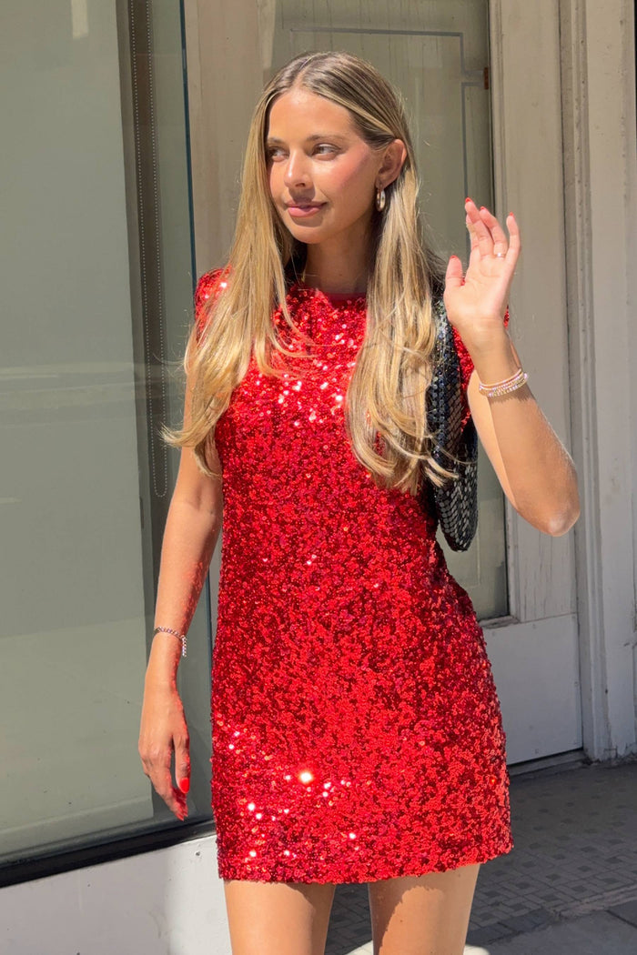 Woman wearing a red sequin dress standing outdoors.