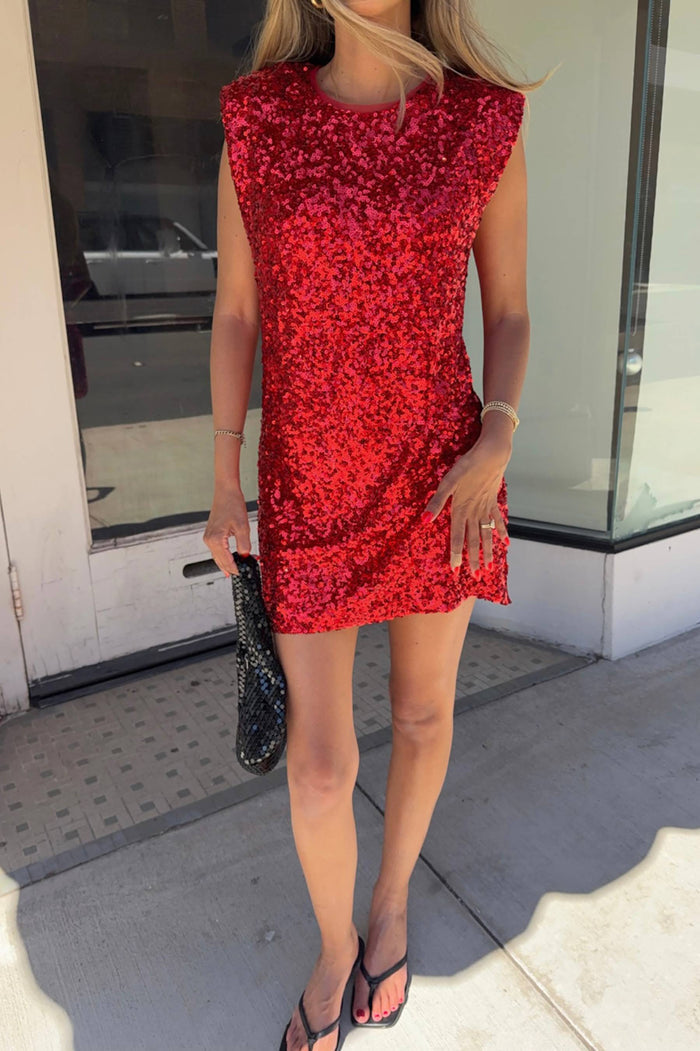Person wearing a red sequin dress standing outside a building.