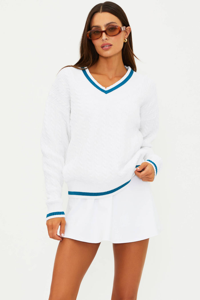 Woman wearing a white long-sleeve dress with blue trim on a white background