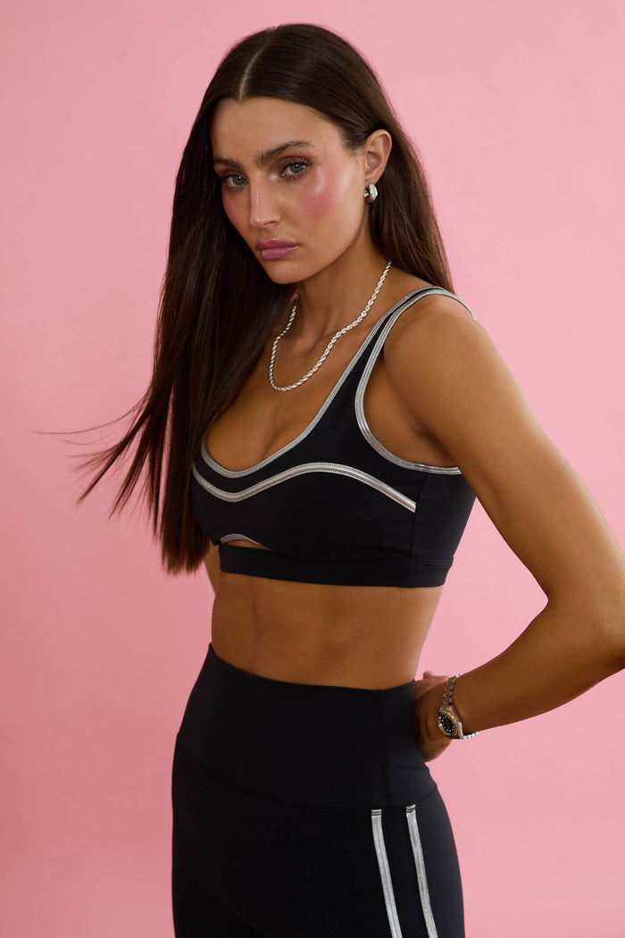 Woman wearing a black sports bra and leggings on a white background