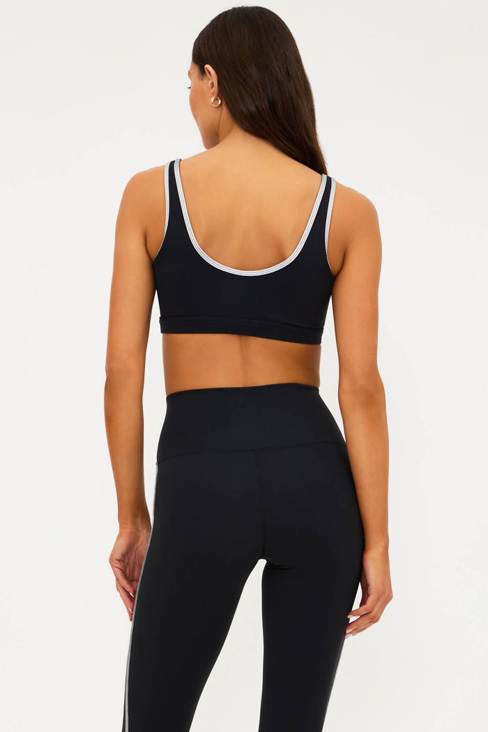 Person wearing a black sports bra and leggings on a white background
