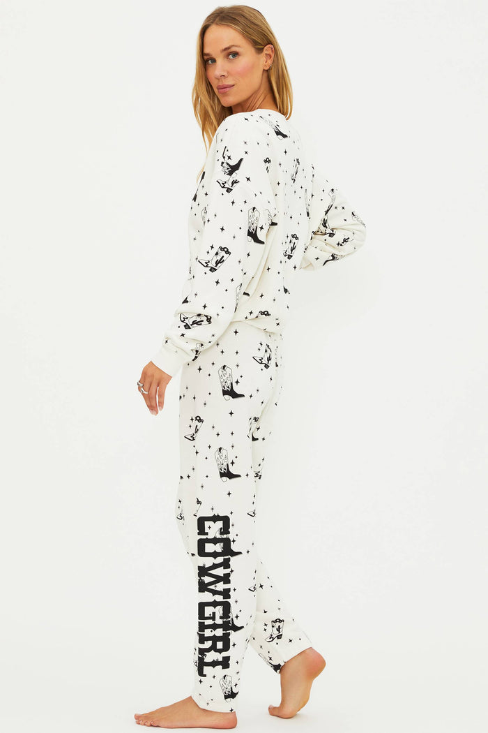 Woman wearing a white onesie with black splatter patterns and 'Cowgirl' text on the leg.