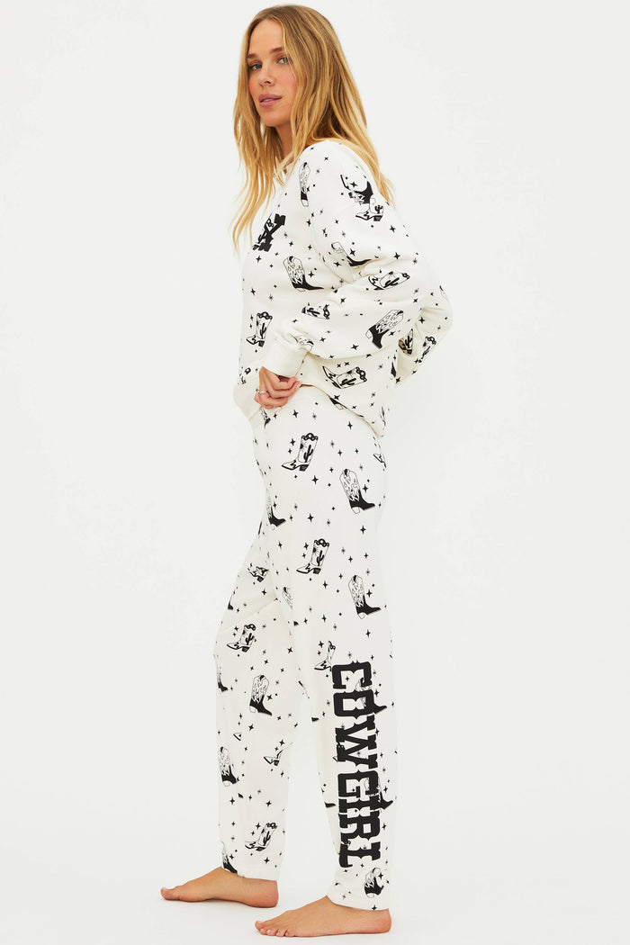 Woman wearing a white pajama set with black cowgirl print on a white background