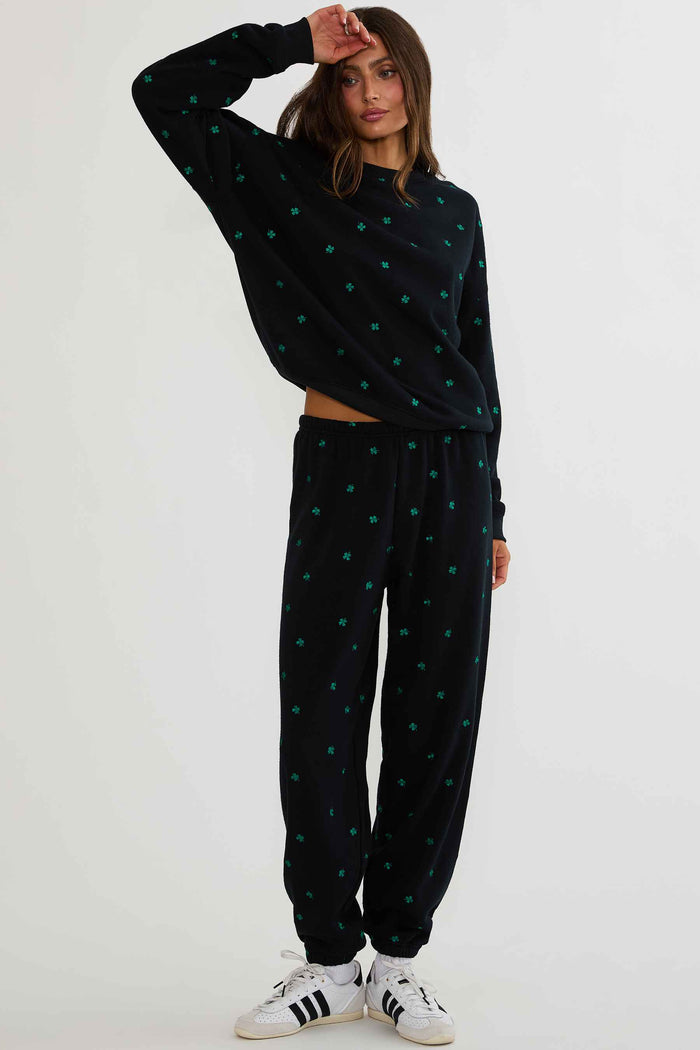 Woman wearing a black polka dot outfit with white sneakers on a white background