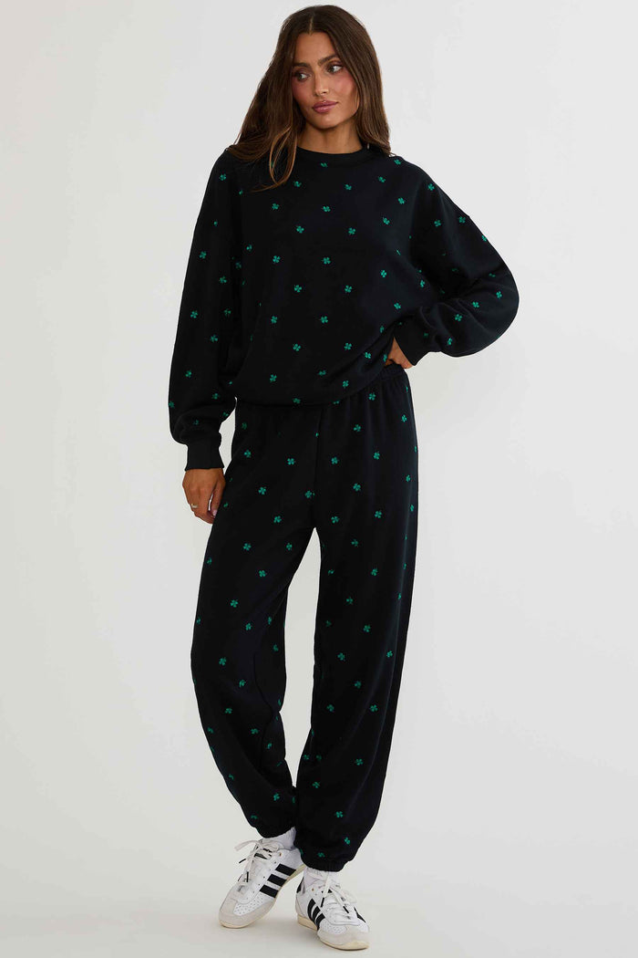Person wearing a black outfit with green heart patterns on a white background