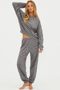 Woman wearing a gray pajama set with red heart patterns on a white background