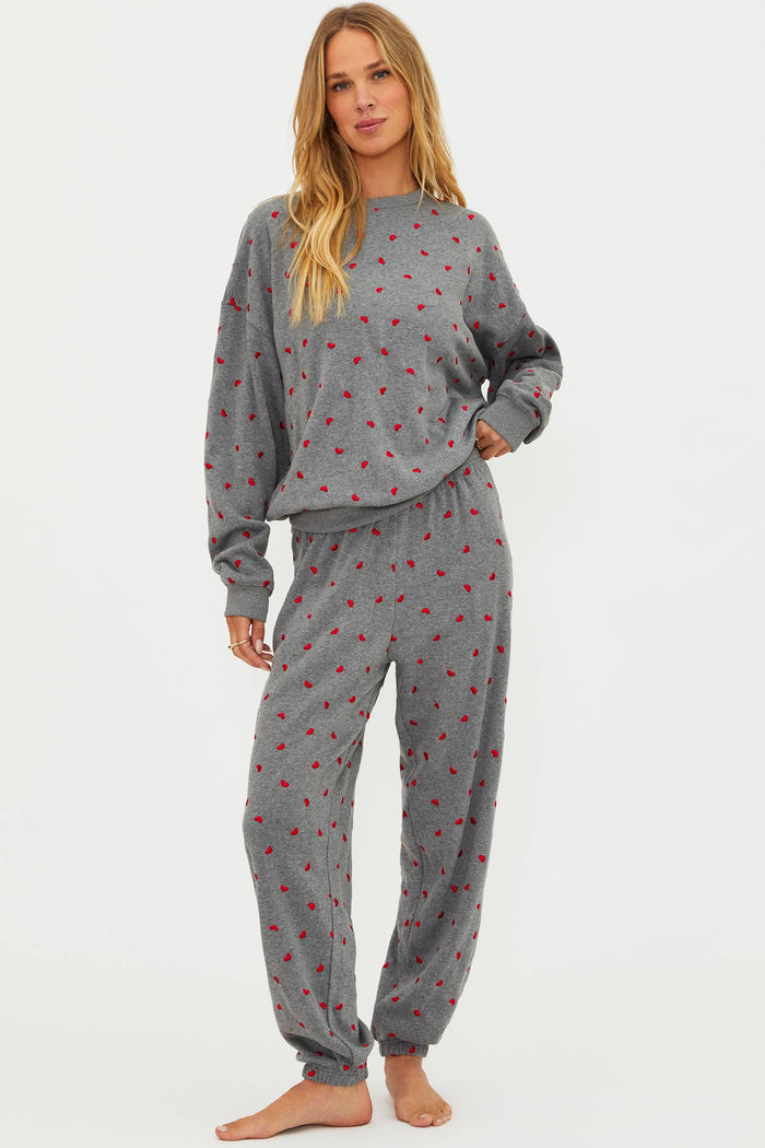 Woman wearing a gray pajama set with red patterns on a white background