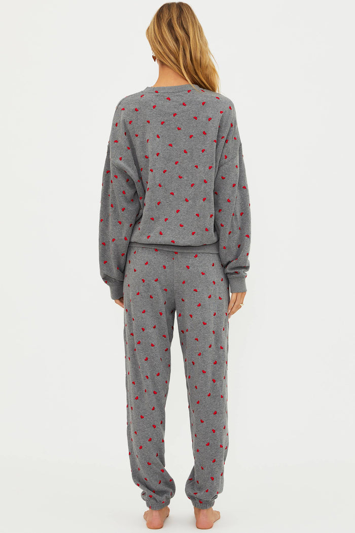 Person wearing a gray pajama set with red patterns on a white background