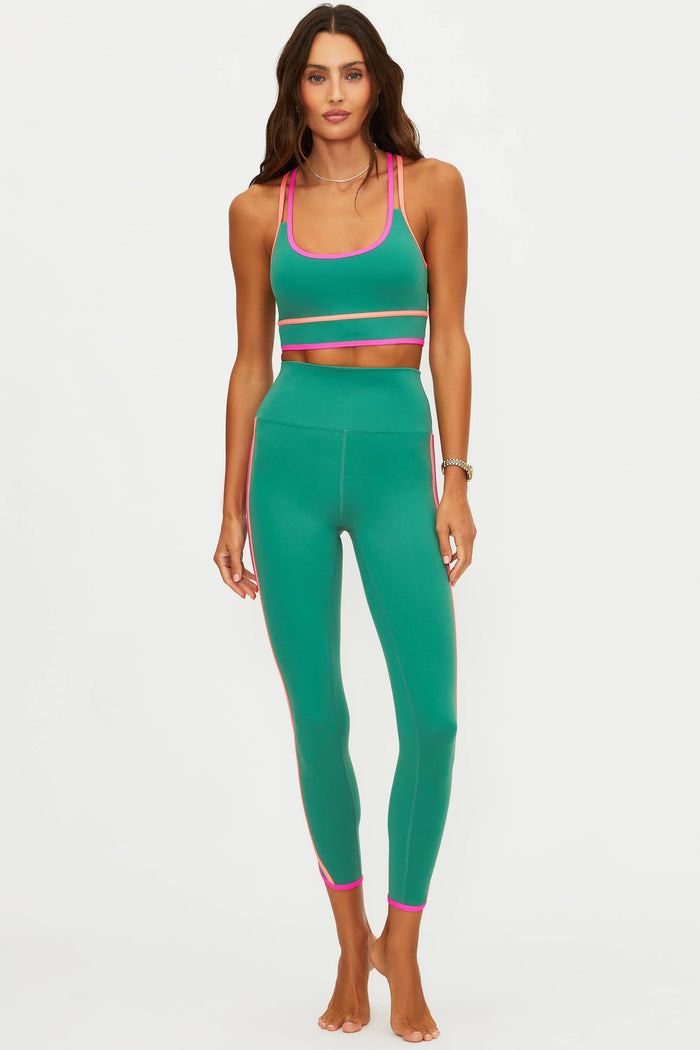 Woman wearing a green athletic outfit with pink accents on a white background