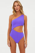 A model wearing an asymmetrical one-shoulder swimsuit in ultra violet color with a side cut-out detail on the waist.