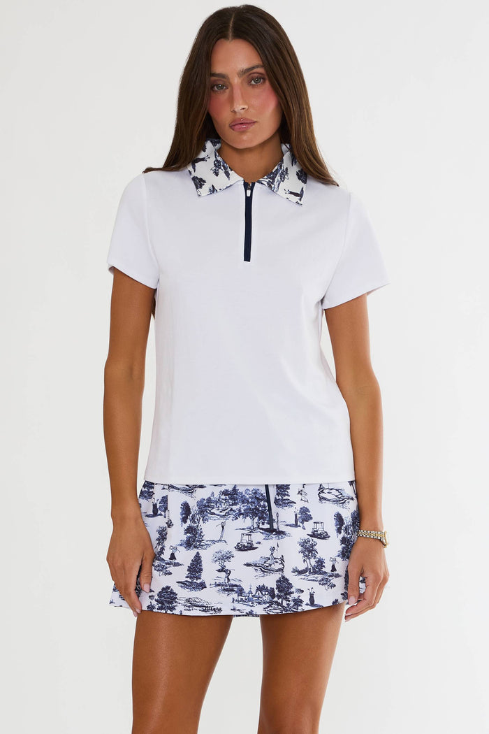 Woman wearing a white polo shirt with blue patterned skirt on a white background
