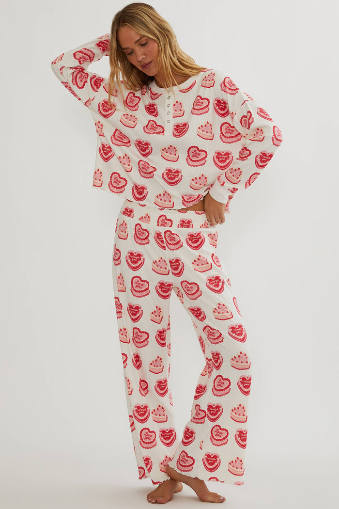 Person wearing a white outfit with red heart patterns on a plain background