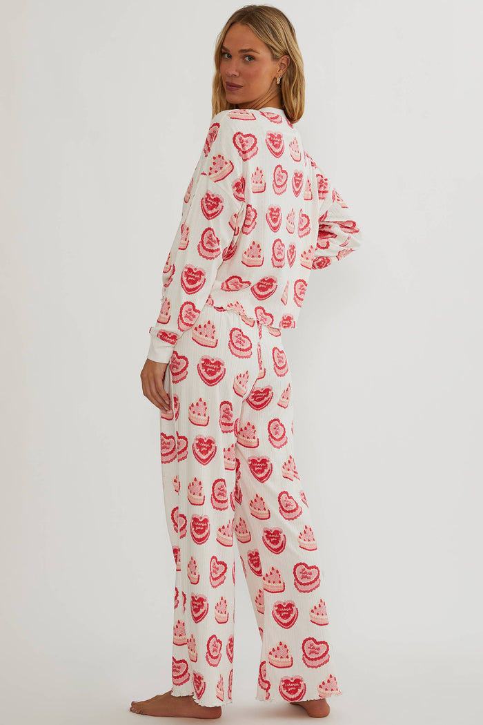 Person wearing a long-sleeve pajama top with red pattern on a white background