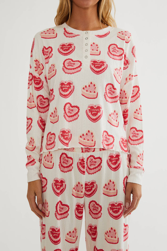 White long-sleeve top and pants with red heart and cake pattern on a white background