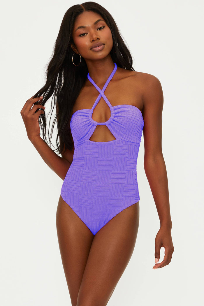 A model wearing a ultra violet terry one-piece swimsuit with an adjustable halter neck and cut out detail.