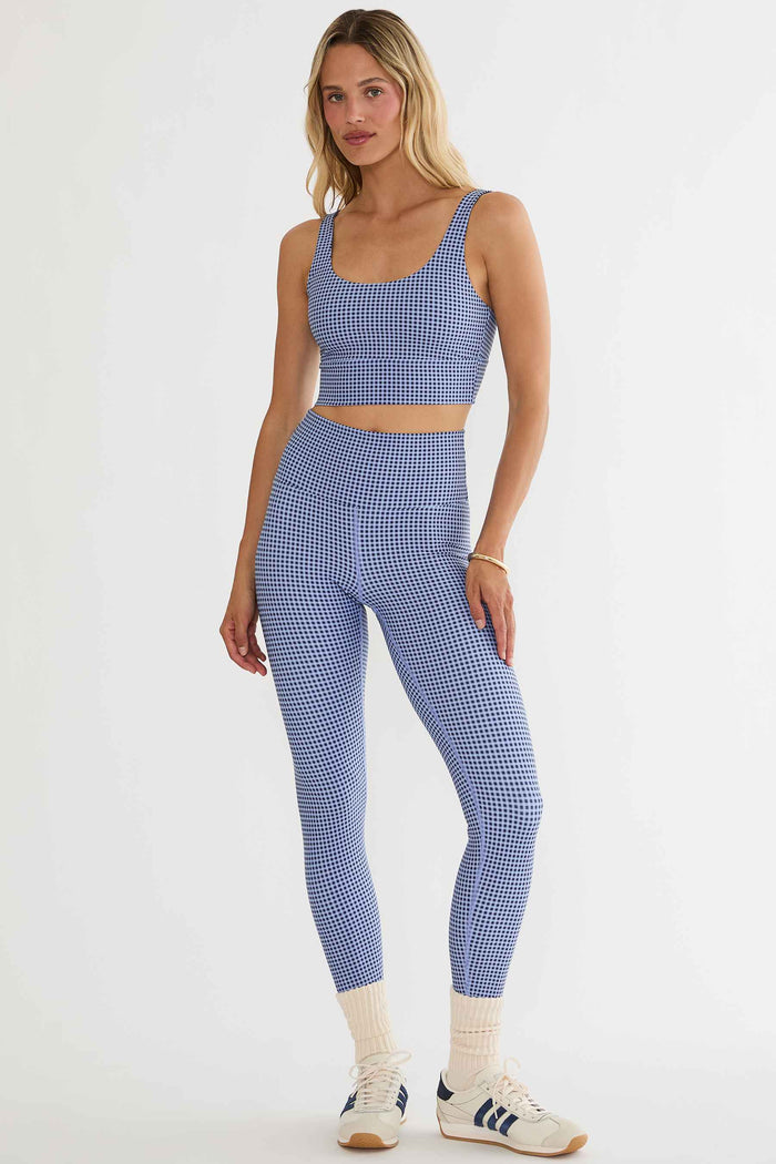 Woman wearing a blue checkered sports bra and leggings set on a white background