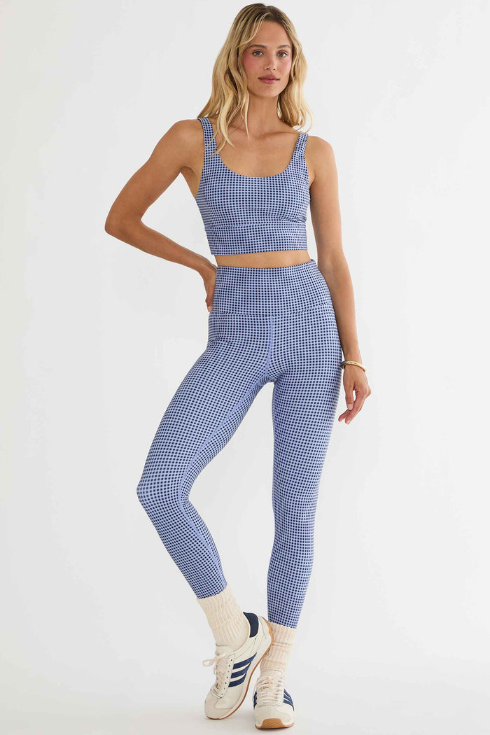 Woman wearing a blue checkered sports bra and leggings set on a white background