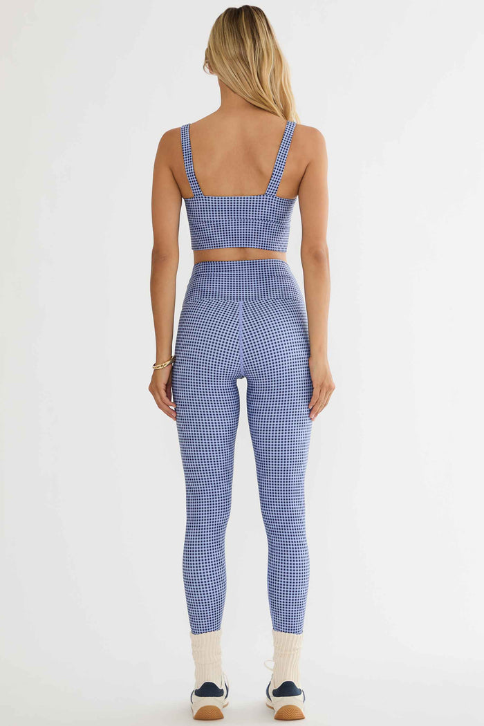 Person wearing a blue and white checkered sports bra and leggings set on a white background