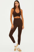 Woman wearing a brown sports bra and leggings set on a white background