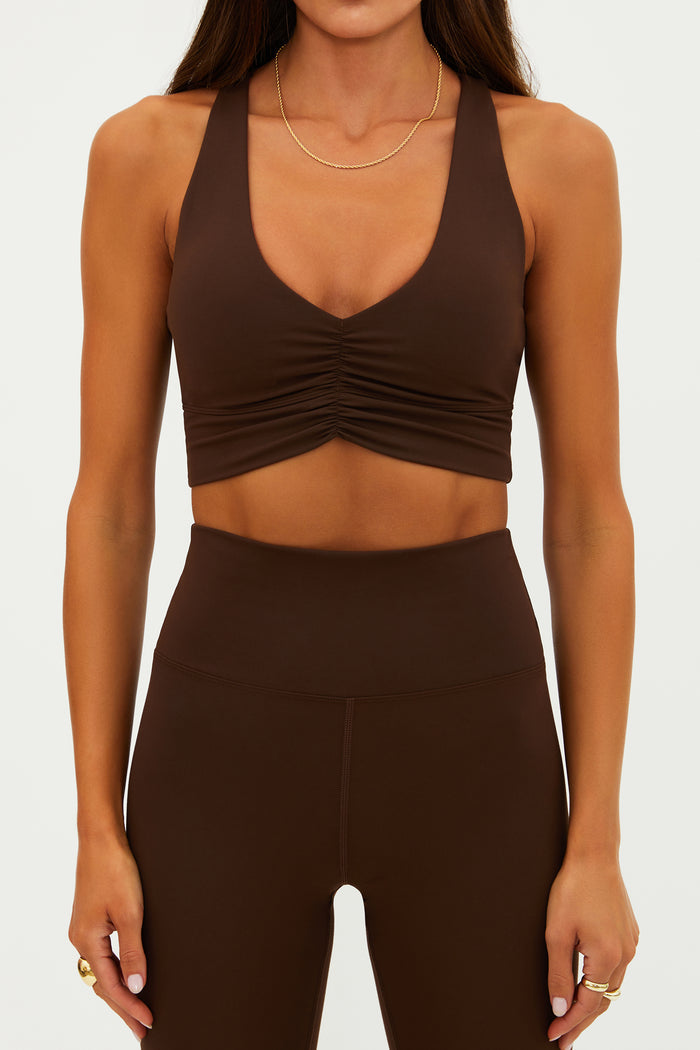 Woman wearing a brown sports bra and leggings set on a white background