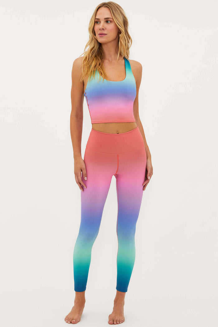 Woman wearing a colorful gradient sports bra and leggings on a white background