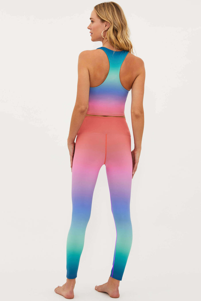 Woman wearing a colorful gradient sports bra and leggings on a white background
