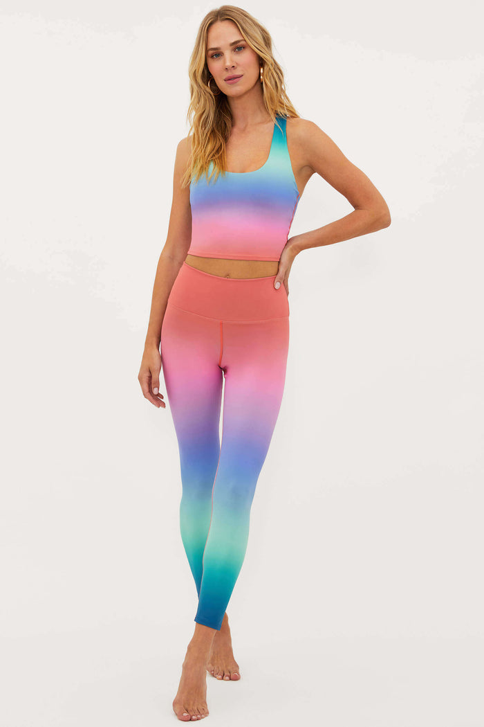 Woman wearing a colorful gradient sports bra and leggings on a white background