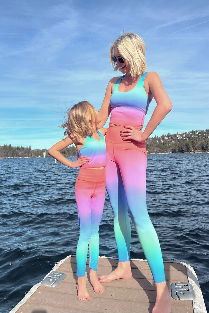 Woman wearing a colorful gradient sports bra and leggings on a white background