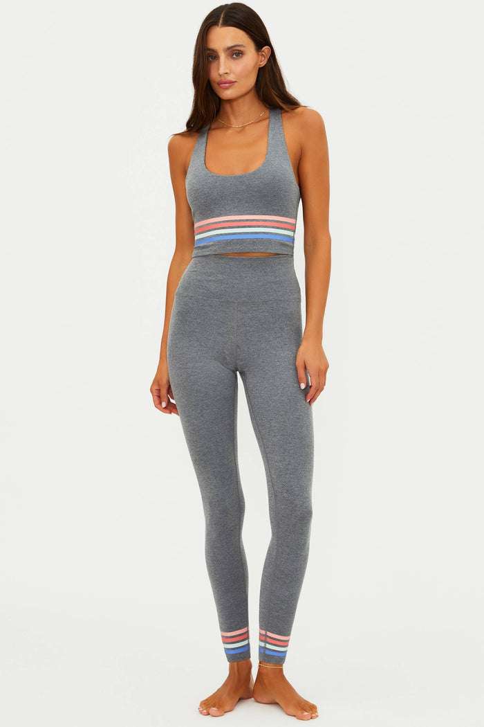 Woman wearing a gray athletic outfit with colorful stripes on a white background