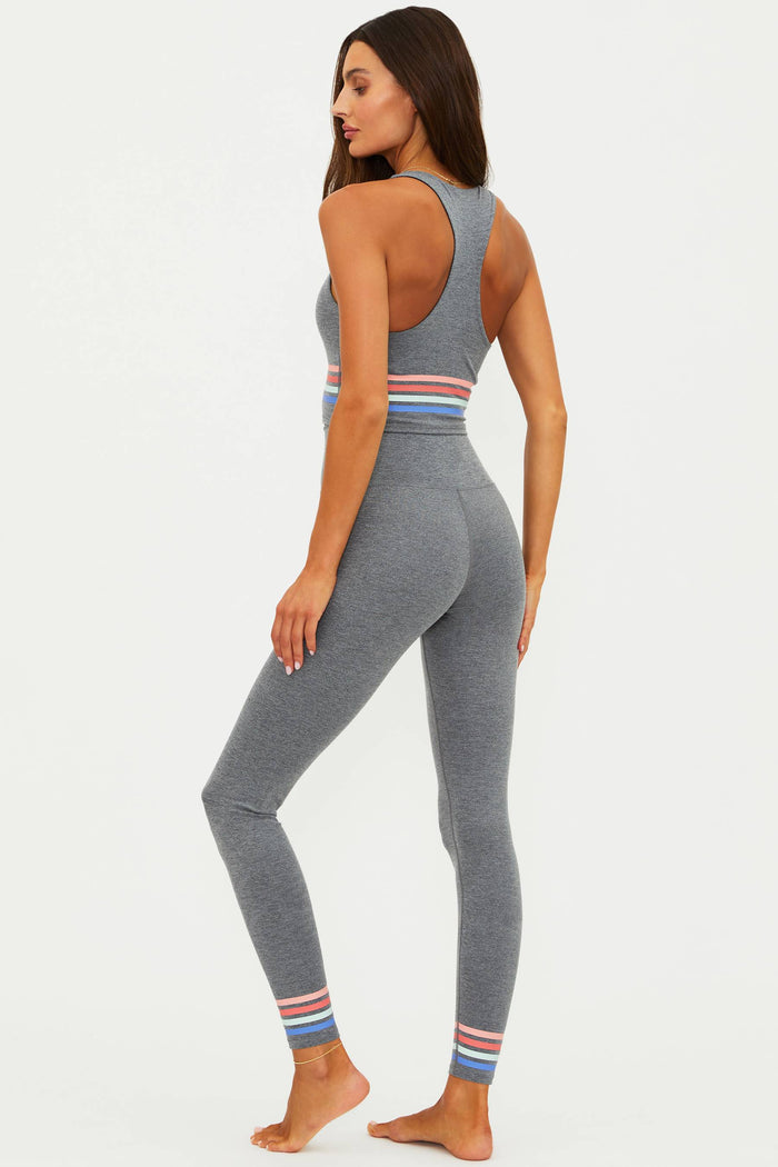 Woman wearing a gray athletic outfit with colorful stripes on a white background