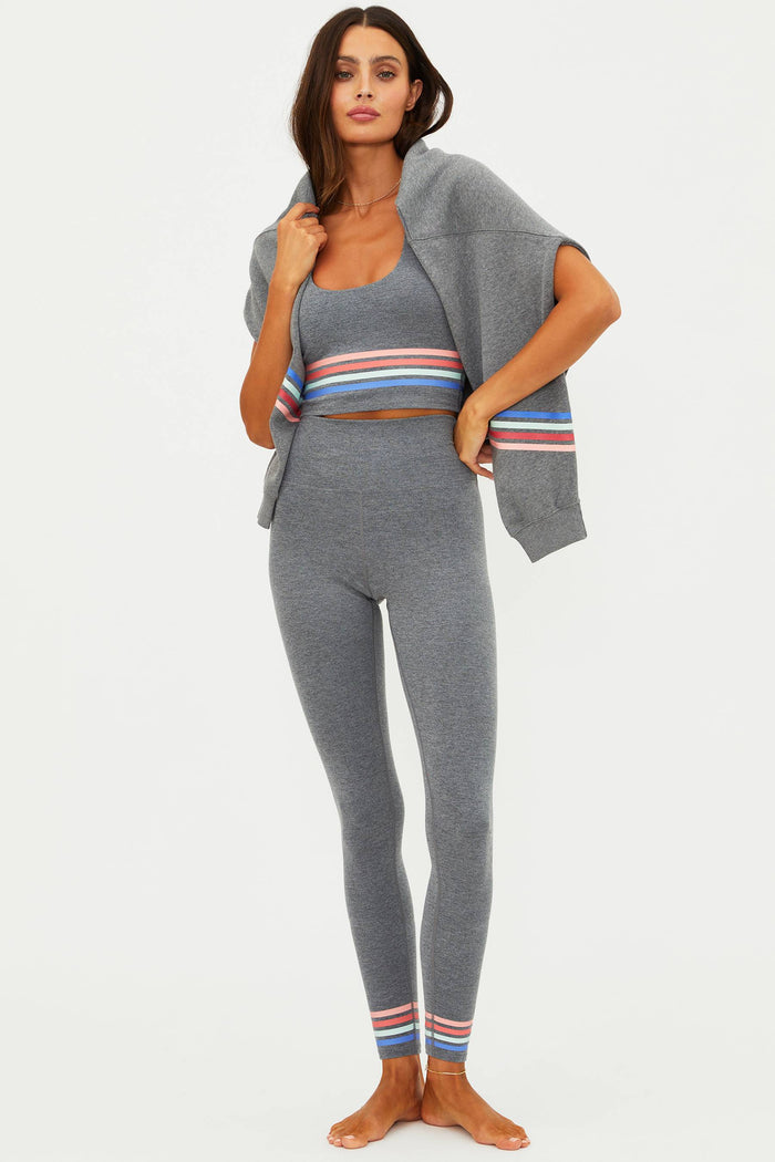 Woman wearing a gray athletic outfit with striped details on a white background