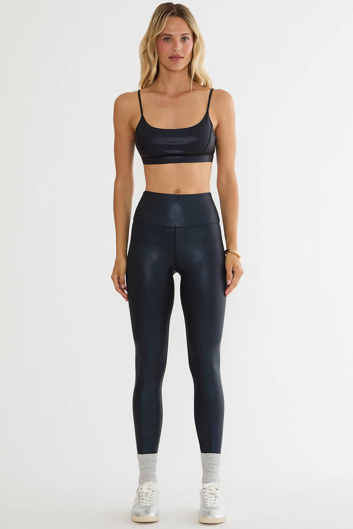 Woman wearing black shiny leggings on a plain white background.