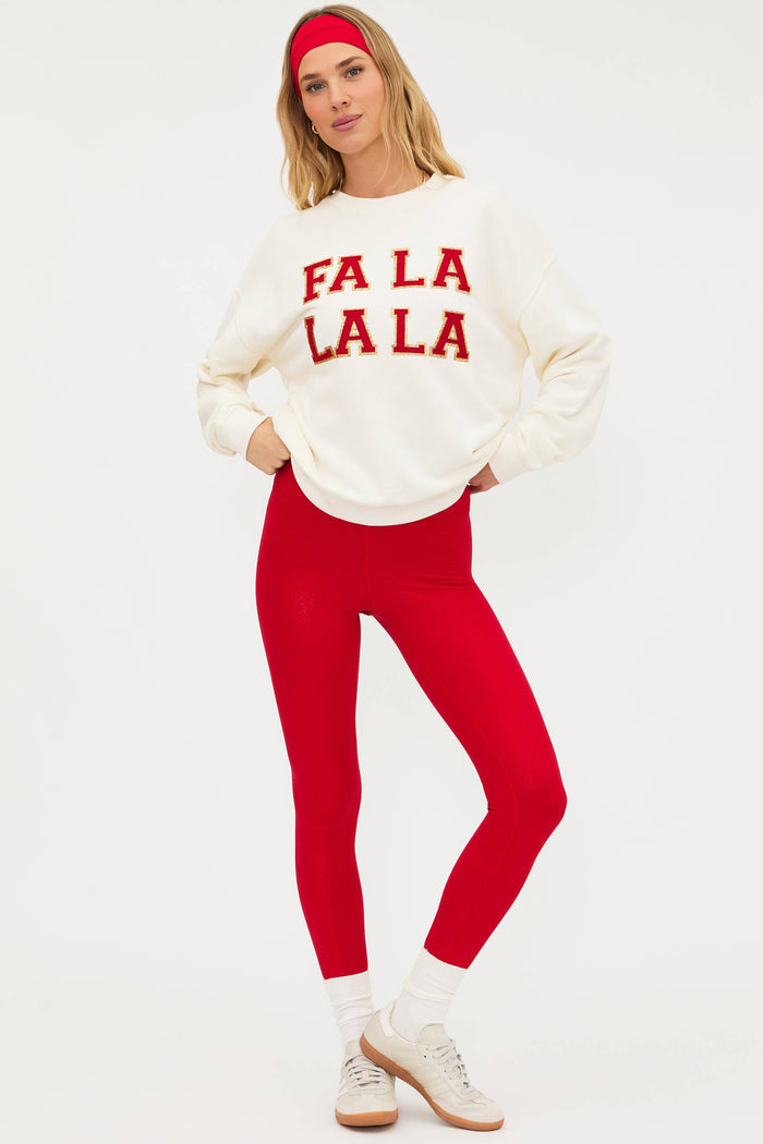 Woman wearing a white sweater with 'FA LA LA LA' text and red pants on a white background