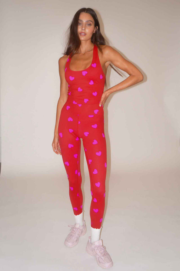 Woman wearing a red outfit with pink heart patterns on a plain background