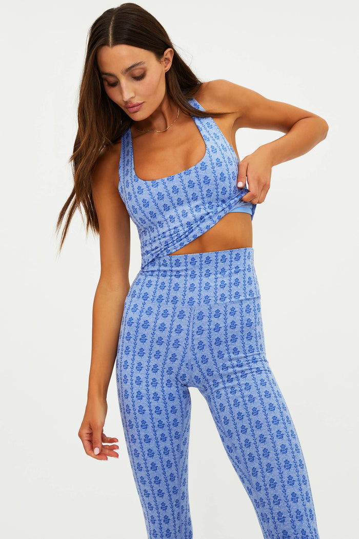 Woman wearing a blue patterned sports bra and leggings on a white background