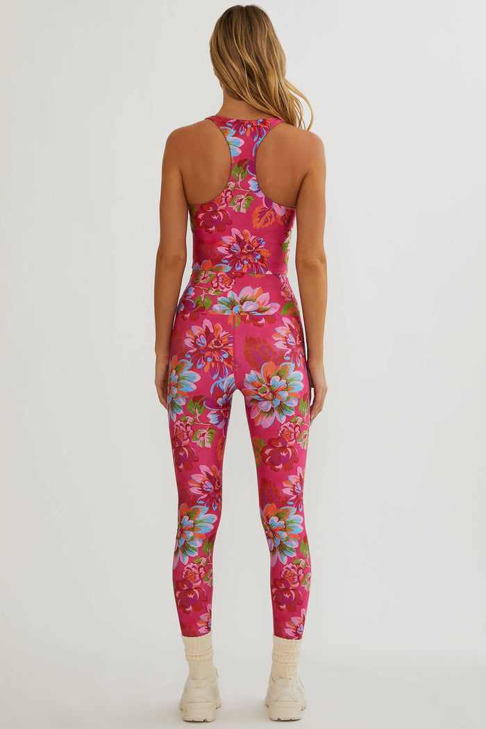 Woman wearing a pink floral jumpsuit on a white background