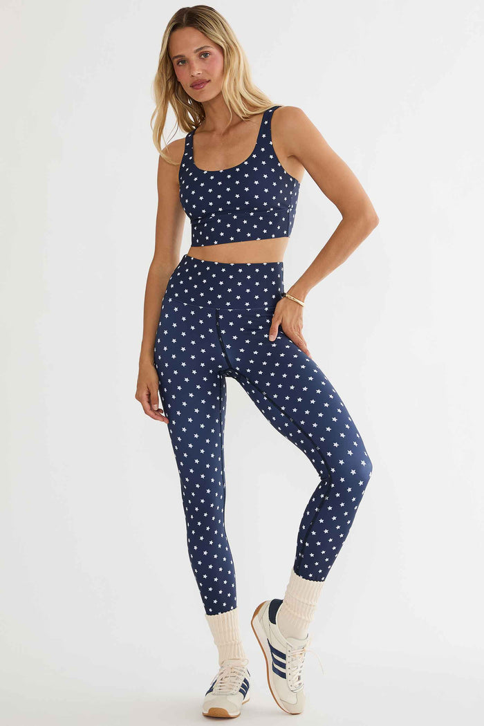Woman wearing a navy blue athletic outfit with white polka dots on a white background
