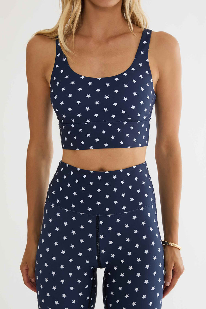 Person wearing a navy blue sports bra and leggings with white star patterns on a white background