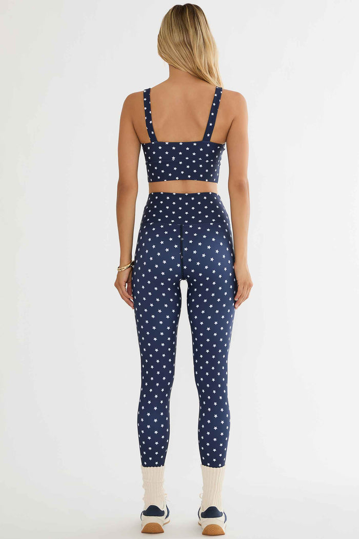 Person wearing a navy blue and white polka dot sports bra and leggings set on a white background