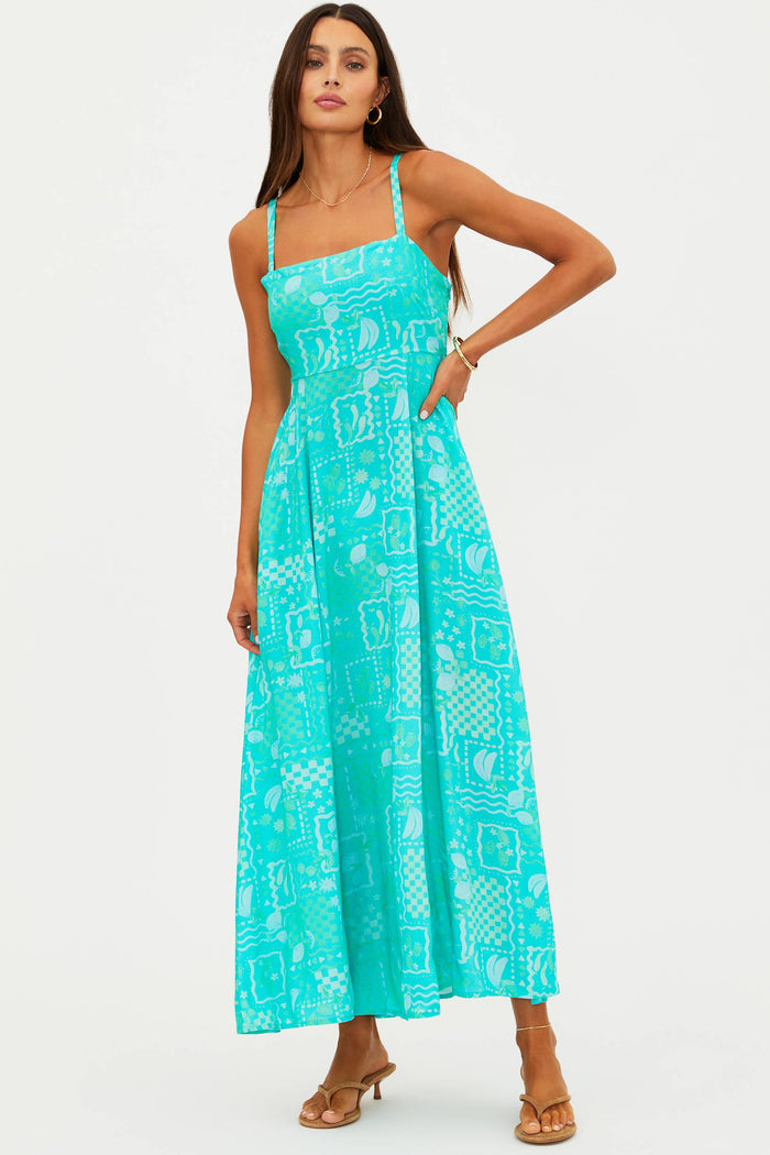Woman wearing a turquoise dress with a white pattern on a white background