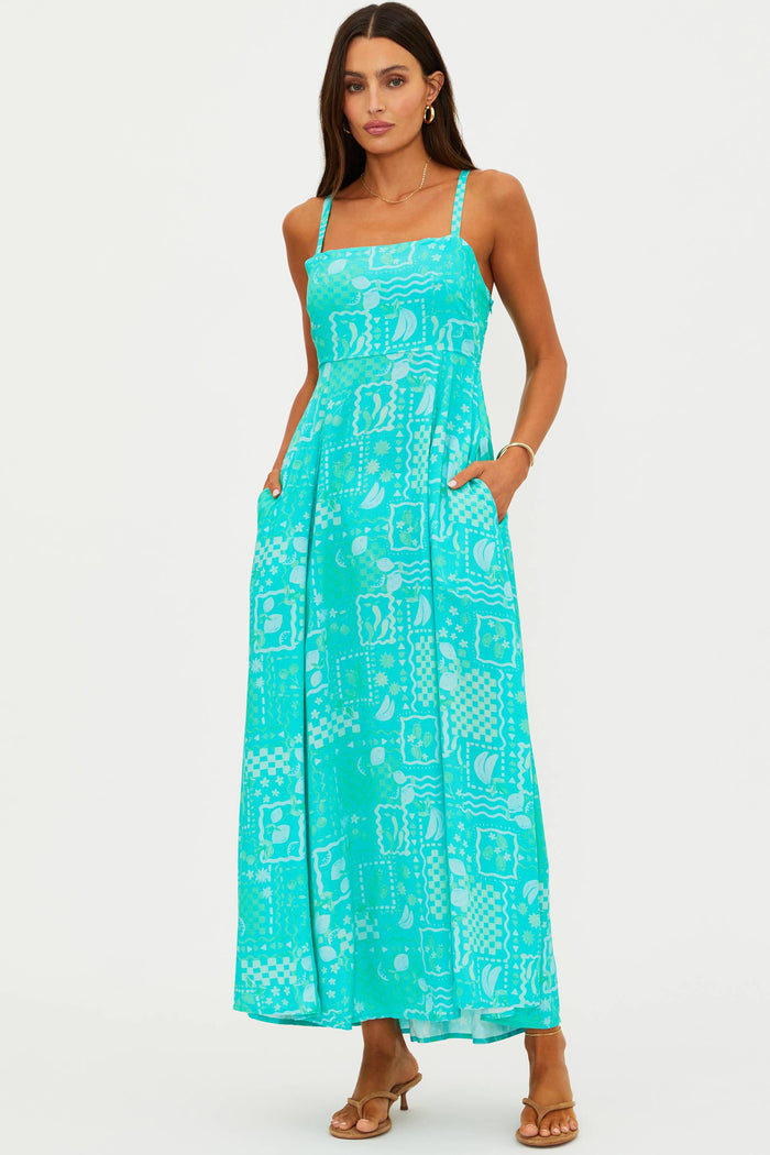 Woman wearing a turquoise dress with a geometric pattern on a white background