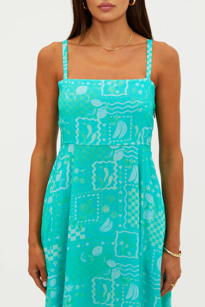 Woman wearing a turquoise dress with a pattern on a white background