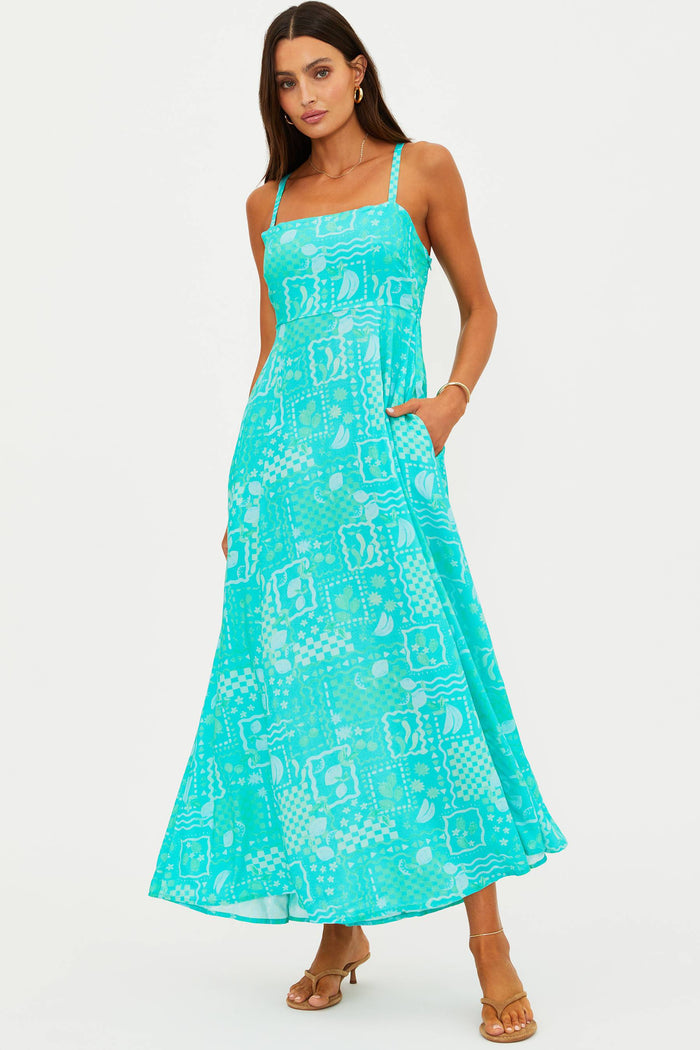 Woman wearing a turquoise patterned dress on a white background