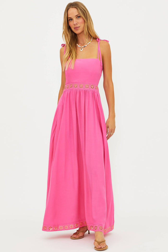 Woman wearing a pink maxi dress with lace details on a white background