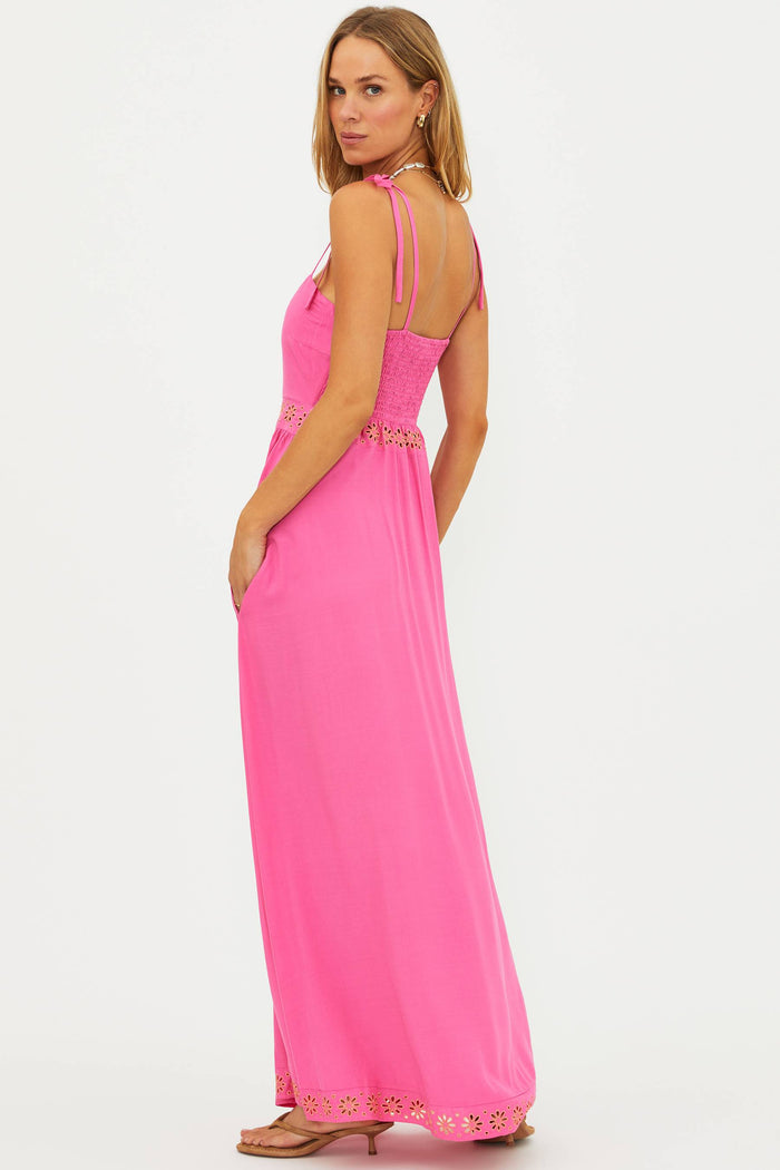 Woman wearing a bright pink maxi dress with thin straps on a white background